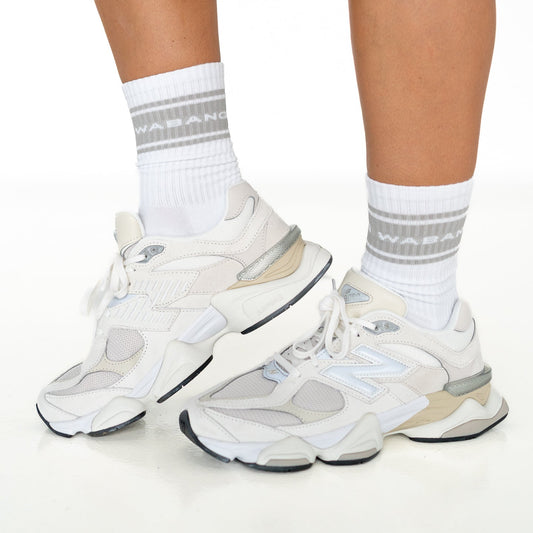White sneakers with gray accents worn with white socks on a white background