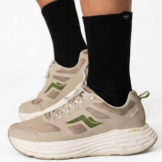 A person wearing beige and olive green athletic sneakers with black Pumpt Apparel crew socks.