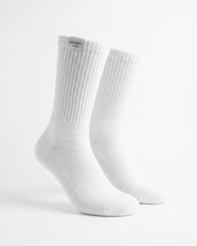 A pair of white ribbed crew socks displayed on invisible forms against a clean white background. The brand name 'PUMPT APPAREL ' is visible on a small black label at the top cuff.